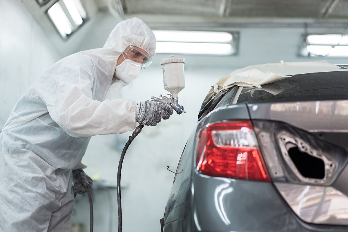 Service technician painting a grey car